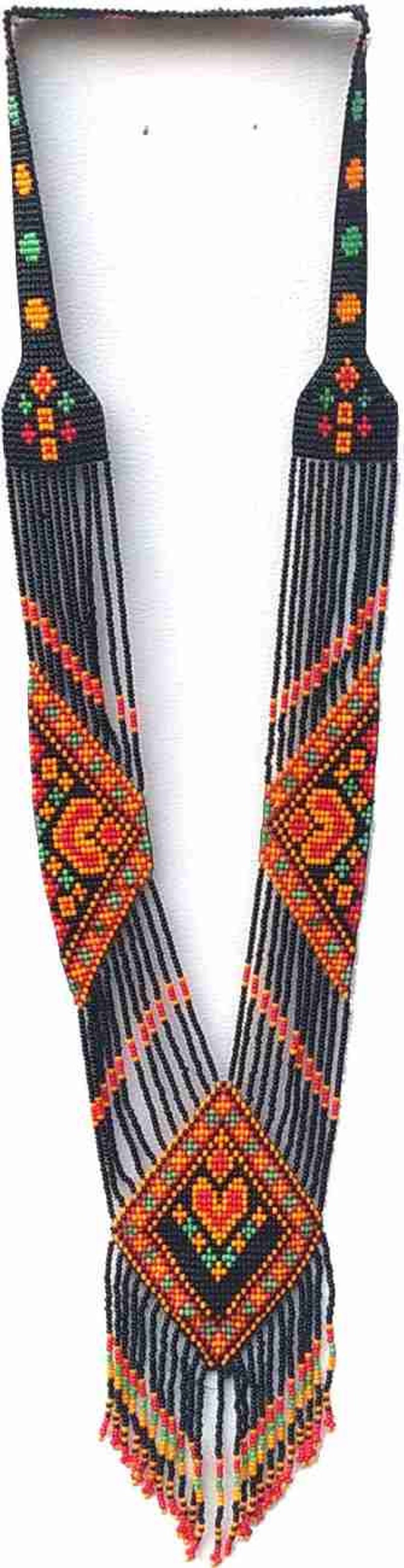 May include: A long black beaded necklace with colourful geometric patterns and fringe. The necklace features a central diamond-shaped design with a heart motif.