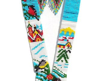 May include: A white beaded necklace with a blue and white fringe. The necklace features a repeating pattern of houses, birds, and trees. The necklace is accented with red, yellow, and green beads.