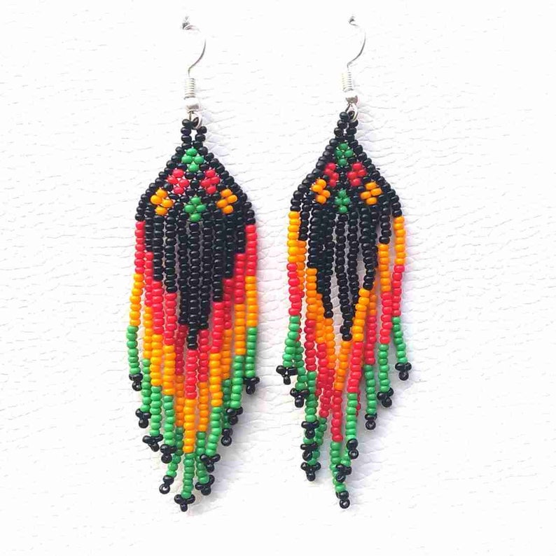 May include: A pair of long, beaded earrings with a black, red, orange, and green colour scheme. The earrings are made of small, round beads and have a fringe-like design.