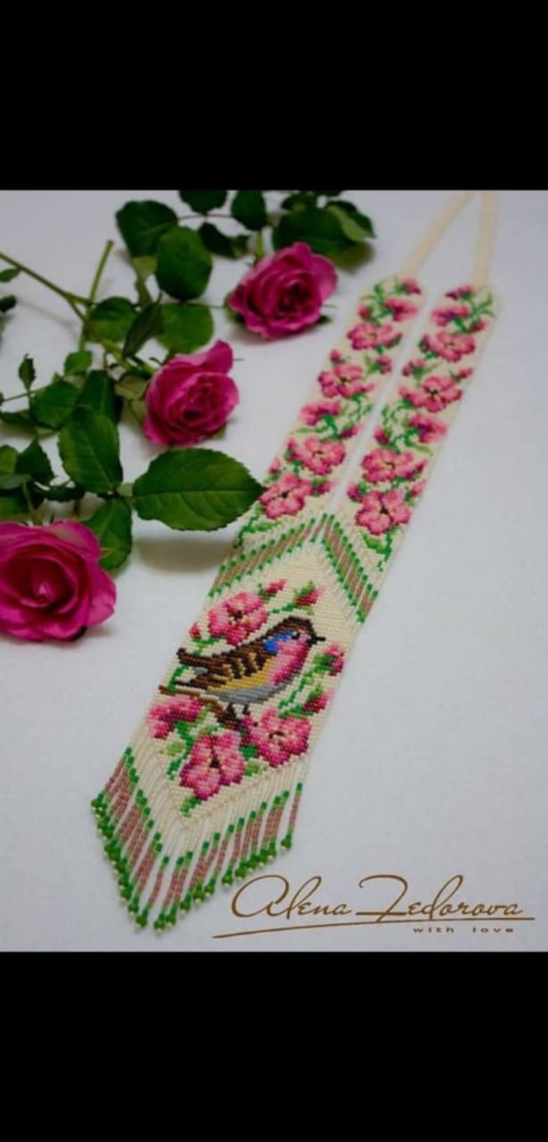 May include: A white beaded necklace with a pink and green floral design and a small bird in the center. The necklace has a fringe at the bottom. The text "Alena Fedorova with love" is at the bottom of the image.