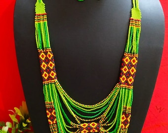 May include: A multi-strand beaded necklace and matching earrings. The necklace is made of green, yellow, red, and black beads. The earrings are long and dangle. The necklace is layered and has a geometric pattern in the center.