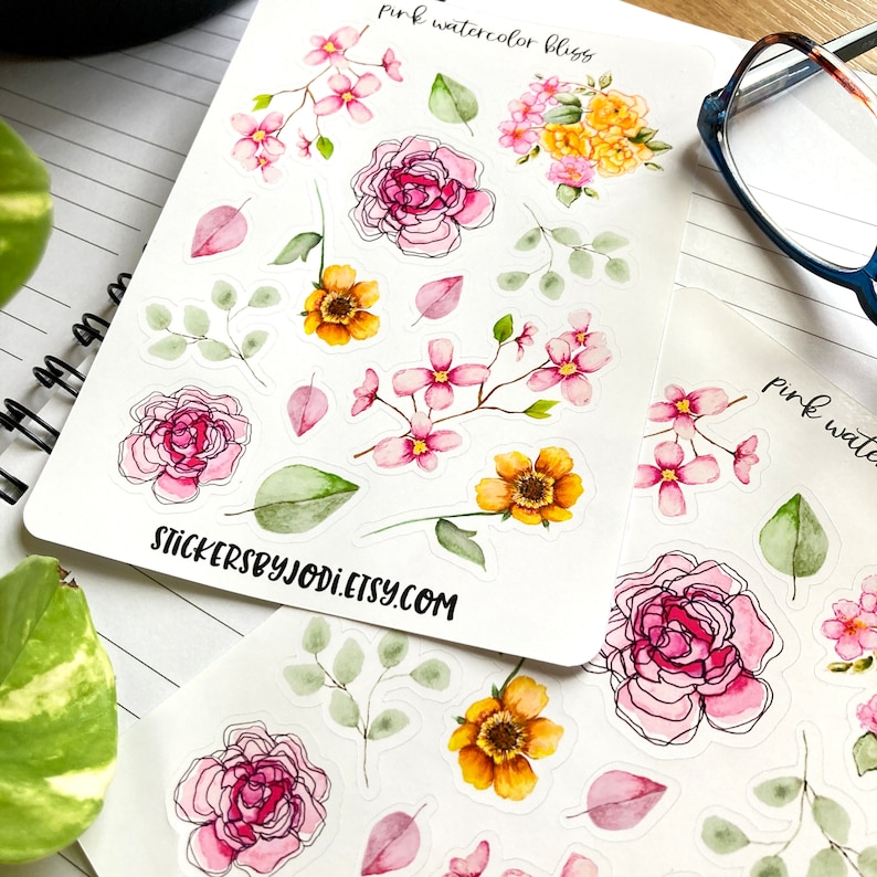 May include: Sheets of floral stickers featuring pink watercolor blossoms, yellow flowers, and green leaves. The stickers have a delicate, hand-painted appearance with black outlines. The text "pink watercolor bliss" and "stickersbyjodi.etsy.com" are visible.