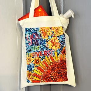 Bolsa de lona hecha a mano con mi obra de arte de acuarela original, bolsa de la compra con cita "Eres el universo" y flores celestiales