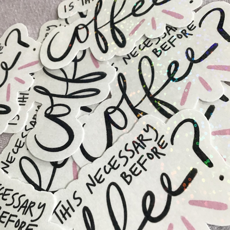 May include: A collection of white stickers with the words "coffee" and "Is this necessary before coffee?" in black script. The stickers have a holographic, glittery finish and pink accents.