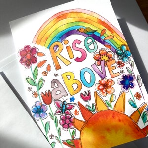 May include: Watercolor greeting card with a rainbow, sun, flowers, and the words "Rise Above." The design features a colorful rainbow arching over the words, with a small bird perched on top. The card is decorated with various flowers and a butterfly.