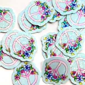 May include: A collection of light blue stickers with a peace sign design. Each sticker features a pink peace symbol encircled by a floral wreath with pink, blue, and yellow flowers. The stickers have a holographic, glittery effect.