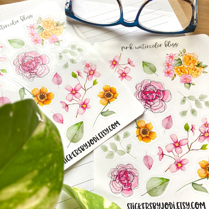 May include: Two sheets of floral stickers with watercolor designs. The stickers feature pink, yellow, and orange flowers, green leaves, and the text "watercolor bliss" and "pink watercolor bliss". The website address stickersbyjodi.etsy.com is also visible.