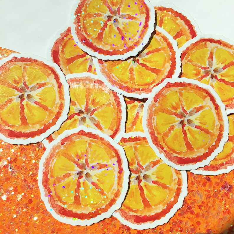 Puede incluir: Una colecci&oacute;n de pegatinas estilo acuarela con rodajas de naranja. Las pegatinas tienen una combinaci&oacute;n de colores amarillo y naranja con un contorno rojo y detalles de purpurina. Las pegatinas est&aacute;n esparcidas sobre una superficie naranja brillante.