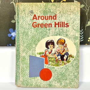 May include: A vintage children's book titled "Around Green Hills" with a green cover featuring an illustration of two children holding rabbits. The cover also includes a blue rectangle and a red circle.