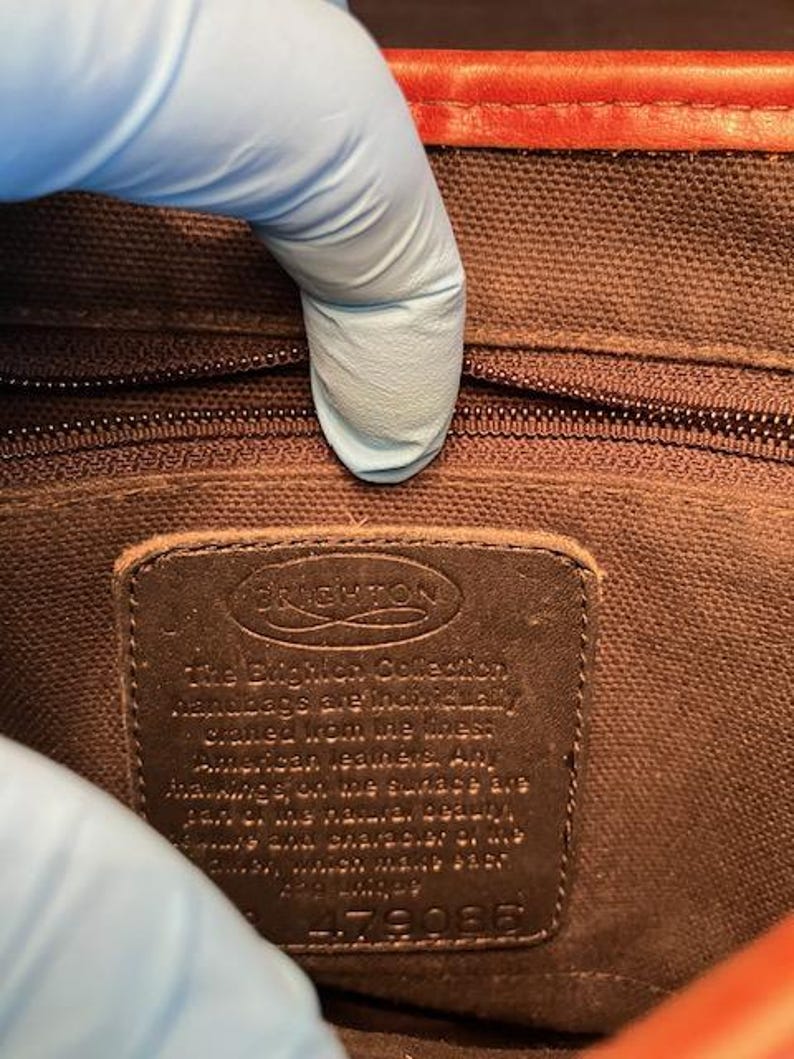 May include: A brown leather tag with the text "The Brighton Collection Handbags are individually crafted from the finest American leathers. Any markings on the surface are part of the natural beauty and character of the leather which will only improve with age." and the number "4179082".