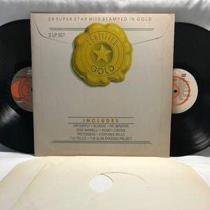 May include: A 2-LP set of vinyl records with a gold certified seal. The album cover features the text "24 Super Star Hits Stamped in Gold" and "Certified Gold". The album includes artists such as Air Supply, Blondie, Pat Benatar, Gino Vannelli, Kenny Loggins, The Pretenders, Stephanie Mills, The Police, and The Alan Parsons Project.