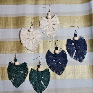 Puede incluir: Cuatro pares de pendientes de borla hechos a mano con cuentas de madera. Dos pares son blancos, un par es azul oscuro y un par es verde oscuro.