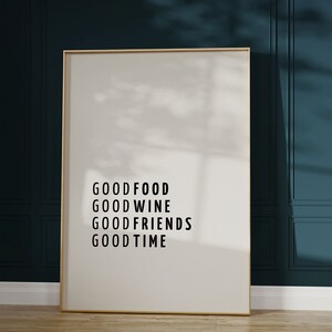 Könnte beinhalten: Ein gerahmter Druck mit dem Text "GOOD FOOD GOOD WINE GOOD FRIENDS GOOD TIME" auf weißem Hintergrund. Der Rahmen ist golden und der Druck hängt an einer dunkelblauen Wand.