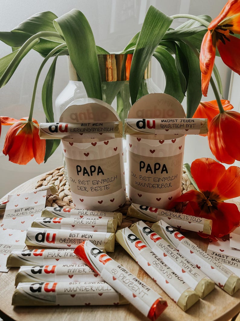 May include: A collection of small wrapped chocolate bars with various messages printed on them. The messages include "Du bist mein lieblingsmensch", "Du bist einfach der beste", "Du bist einfach wunderbar", "Geburtstag", "F&uuml;r alles, f&uuml;r uns", "Du bist mein gr&ouml;&szlig;ter Fan", "F&uuml;r mich", "Munter, immer", "Gibst immer 100 Prozent", "Bist einfach wunderbar", "Du bist das beste unserer Familie", "Pflegs mich gesund", "Jagst morgen weiter", "Gutes Nacht-Kasse", "Ein Joker".