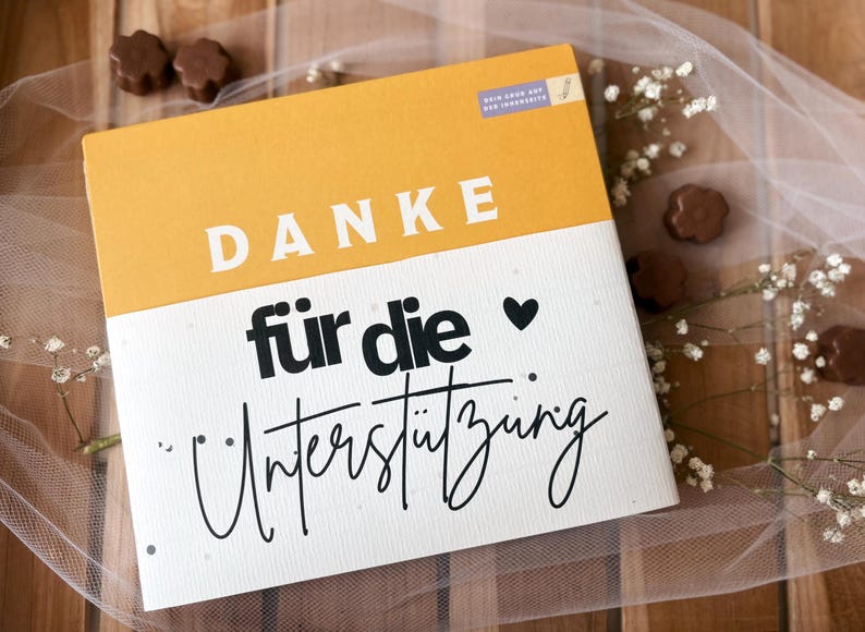 May include: A greeting card with the German word "DANKE" in white block letters on a yellow background. Below, the words "f&uuml;r die Unterst&uuml;tzung" are written in black script. A black heart is next to the word "die".