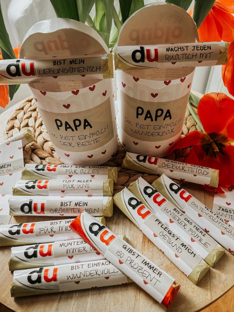 May include: A collection of small wrapped chocolate bars with the word "du" printed on them. Each bar has a different message printed on the wrapper, such as "You are my biggest fan" and "You are simply wonderful".