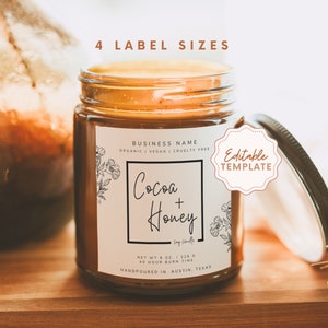 May include: A candle label template featuring a floral design and the text "Cocoa + Honey". The label is editable and comes in four sizes. The candle is in a clear glass jar with a brown lid. The label is on a wooden surface with dried flowers in the background.