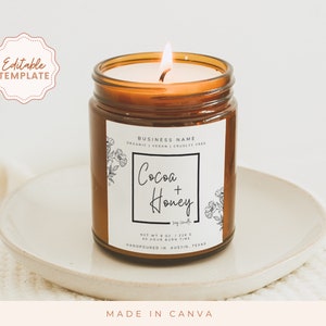 May include: A brown glass candle jar with a white label. The label has a black border and features the text "BUSINESS NAME", "ORGANIC | VEGAN | CRUELTY FREE", "Cocoa + Honey", "Soy Candles", "NET WT 8 OZ / 226 G", "40 HOUR BURN TIME", and "HANDPOURED IN AUSTIN, TEXAS".