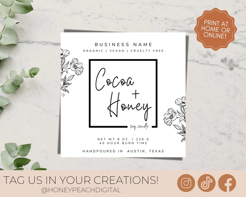 May include: A white label with black text and floral illustrations for a soy candle called "Cocoa + Honey". The label states that the candle is organic, vegan, and cruelty-free. It also states that the candle is hand-poured in Austin, Texas. The label includes the candle's net weight (8 oz / 226 g) and burn time (40 hours).