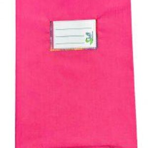 May include: A bright pink rectangular notebook cover featuring a centered white rectangular label with three horizontal lines for writing and a small green logo on the right side. The cover has a smooth, solid-colored fabric texture.