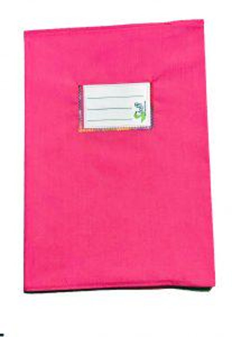 May include: A bright pink rectangular notebook cover featuring a centered white rectangular label with three horizontal lines for writing and a small green logo on the right side. The cover has a smooth, solid-colored fabric texture.
