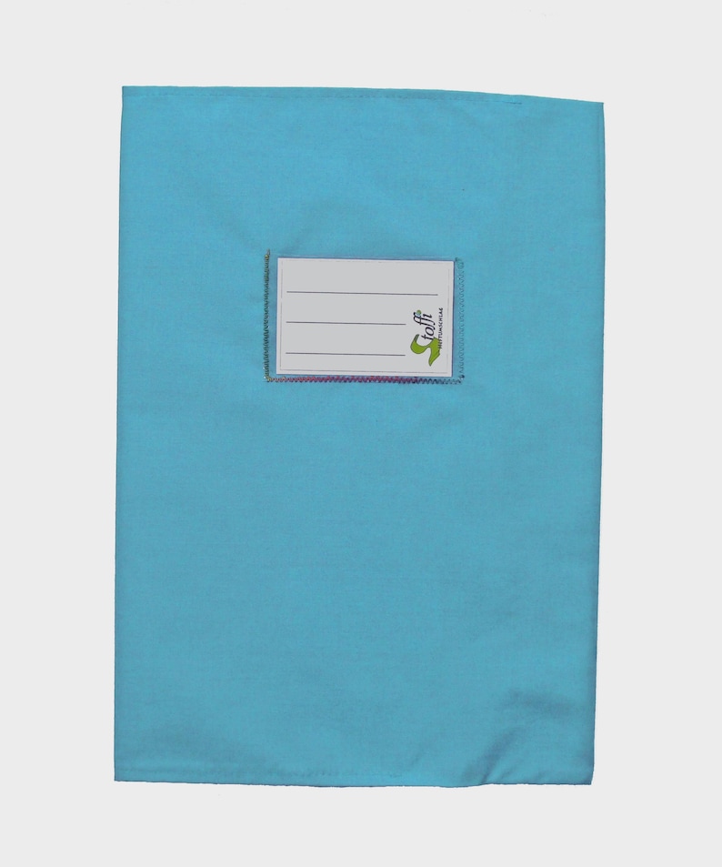 May include: A rectangular light blue fabric book cover featuring a centered white rectangular label with three horizontal lines for writing. The label includes the green text "Stoffi" and a small green graphic icon on the right side.