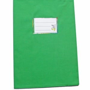 May include: A bright green rectangular fabric book cover featuring a white rectangular label with three horizontal lines for writing and the text "toffi" printed in yellow and black. The label is bordered by a thin, iridescent, multi-colored trim.