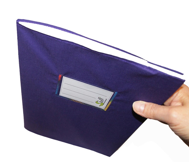 May include: A deep purple fabric-covered notebook featuring a rectangular white label with four horizontal lines for writing. The label is stitched onto the cover with multi-colored thread and includes the green text "Stoff" and "notizbuch".