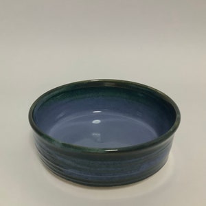 May include: A blue and green ceramic bowl with a glazed finish. The bowl has a rounded shape and a wide rim.