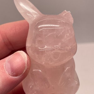 May include: A pink rose quartz carving of a Pikachu, a popular character from the Pokemon franchise.