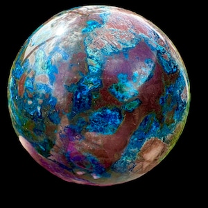 Puede incluir: Una esfera azul, verde y marrón con un patrón de mármol. La esfera está hecha de un material natural y tiene una superficie lisa y pulida.