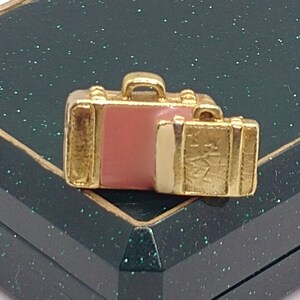 Vintage broche in de vorm van een koffer in goudkleur met email.  Een goed cadeau voor reisliefhebbers.