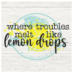 May include: A teal and yellow circle with a lemon slice and a tree inside. The text "where troubles melt like lemon drops" is written in black around the circle. The text "Alba, Texas" is written in black at the bottom of the circle.