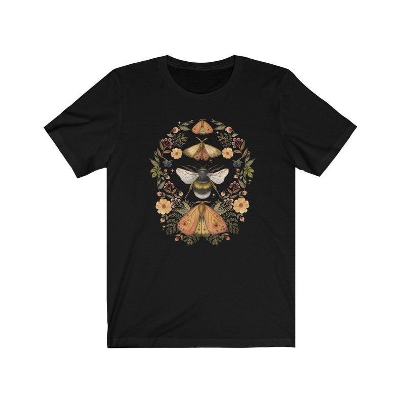 K&ouml;nnte beinhalten: Schwarzes T-Shirt mit einem floralen Kranz-Design mit einer Biene und Motten in Gelb-, Orange- und Braunt&ouml;nen.