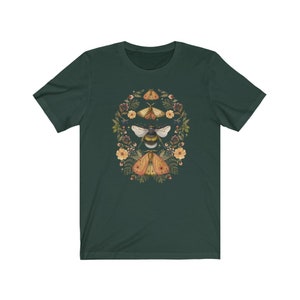 K&ouml;nnte beinhalten: Ein dunkelgr&uuml;nes T-Shirt mit einem kreisf&ouml;rmigen Design, das eine Biene und zwei Motten zeigt, die von Blumen und Bl&auml;ttern umgeben sind.