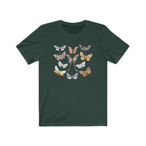 May include: Dark green t-shirt featuring a collection of watercolor butterflies in various colors. The butterflies are arranged in a symmetrical pattern, with a central pair and surrounding insects in shades of pink, yellow, and gray.