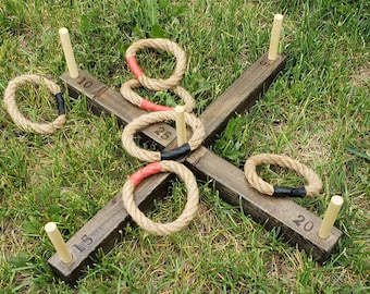 May include: A wooden ring toss game with five rope rings. The rings are brown and have red and black accents. The game has five wooden posts with numbers 5, 10, 15, 20, and 25 printed on them.