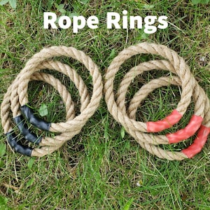 May include: Six circular rope rings arranged in two groups of three. The left group features black rubberised grips, while the right group features red rubberised grips. The text Rope Rings is displayed in white at the top of the image.