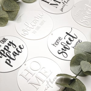 Könnte beinhalten: Fünf runde, weiße Acrylschilder mit schwarzer Beschriftung. Die Schilder sagen "Willkommen in unserem Zuhause", "Unser glücklicher Ort", "Zuhause, süßes Zuhause", "Zuhause, süßes Zuhause" und "Zuhause, süßes Zuhause".