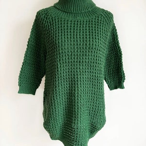 May include: A green knitted turtleneck sweater with a loose fit and a textured pattern.