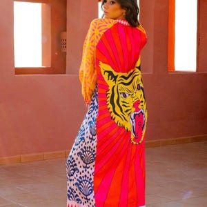May include: A long, colorful dress with a tiger graphic on the back. The dress features a mix of patterns and colors, including yellow, pink, and blue. The word "BRI" is printed at the bottom of the dress.