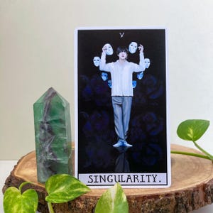 May include: A tarot card with a dark blue background and a man in a white shirt holding up white masks. The card is titled "Singularity."