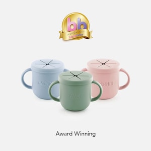 May include: Three silicone cups with lids and handles. The cups are in blue, green, and pink. Each cup has a name on it: "Llewellyn", "Alex", and "Isabella". The cups are award-winning.