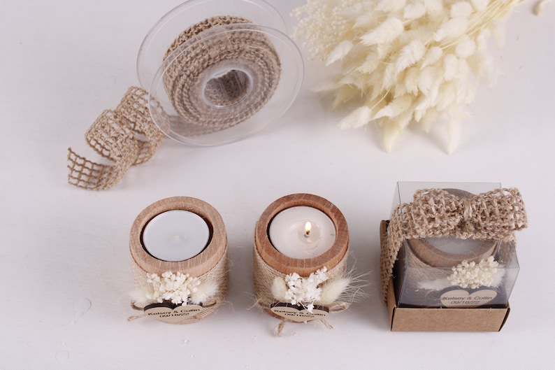 Pu&ograve; includere: Tre piccoli portacandele in legno con un nastro di juta e fiori secchi. Ogni portacandele contiene una piccola candela da t&egrave; bianca. Le candele sono in una scatola trasparente con un fiocco di juta.