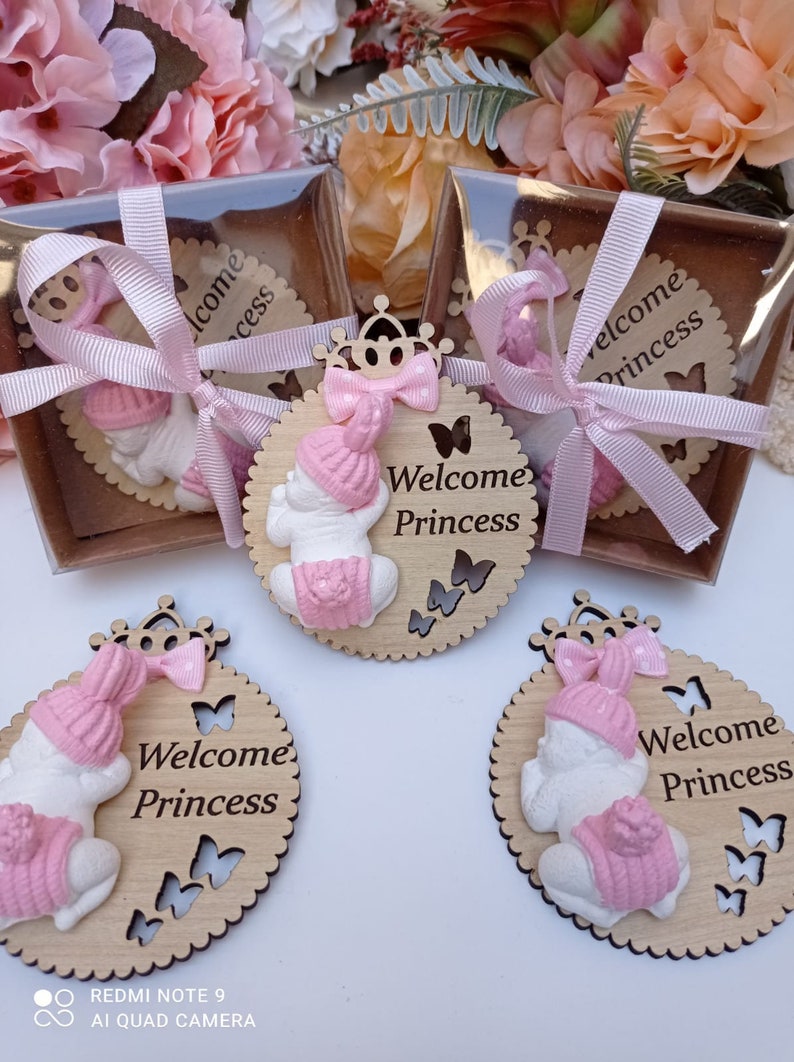 Op de afbeelding: Vier houten babymeisjes welkom borden met een roze en witte babypop, een roze strik en de tekst "Welkom Prinsesje" op elk bord.