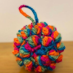Pu&ograve; includere: Un ornamento lavorato a uncinetto colorato con un anello per appenderlo. L'ornamento &egrave; fatto di filato in tonalit&agrave; di arancione, rosa, blu e verde.