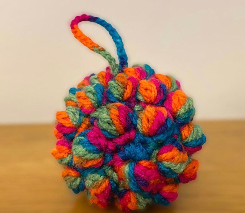Pu&ograve; includere: Un ornamento lavorato a uncinetto colorato con un anello per appenderlo. L'ornamento &egrave; fatto di filato in tonalit&agrave; di arancione, rosa, blu e verde.