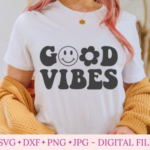 K&ouml;nnte beinhalten: Ein wei&szlig;es T-Shirt mit dem Text "GOOD VIBES" in schwarzen Retro-Lettern. Ein Smiley und eine Blume sind im Text enthalten.
