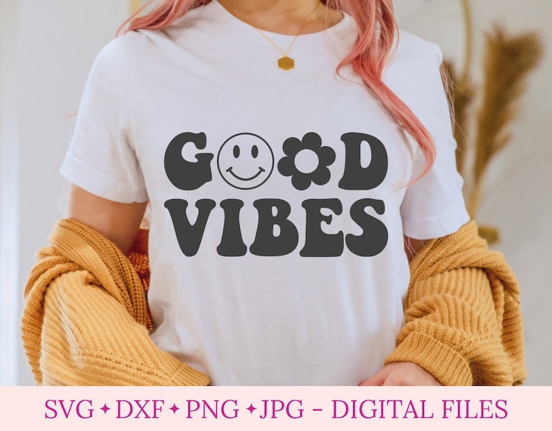 K&ouml;nnte beinhalten: Ein wei&szlig;es T-Shirt mit dem Text "GOOD VIBES" in schwarzen Retro-Lettern. Ein Smiley und eine Blume sind im Text enthalten.