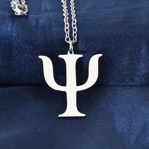 May include: A silver necklace featuring a Psi (Ψ) pendant, set against a dark blue backdrop. The pendant is suspended from a fine chain, creating a minimalist and stylish design. The necklace is a symbol of psychology.